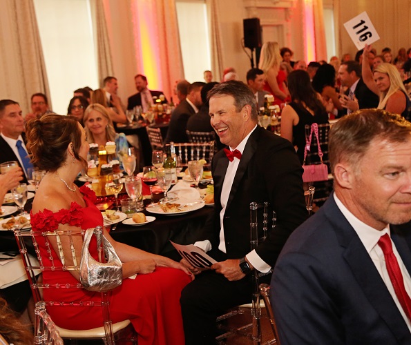 couple laughing at their table while woman holds up her bid paddle in background